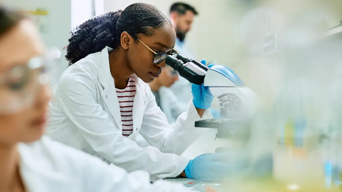 a woman looking into a microscope 