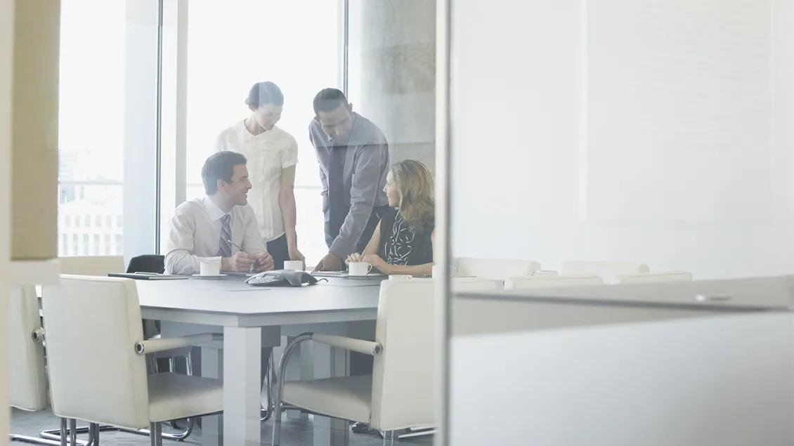 four people in a meeting room at a distance
