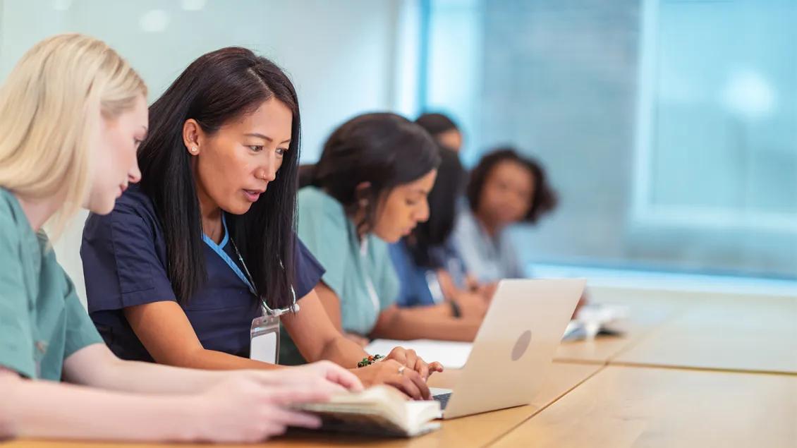 group of medical professionals in an educational class with a laptop and notebooks