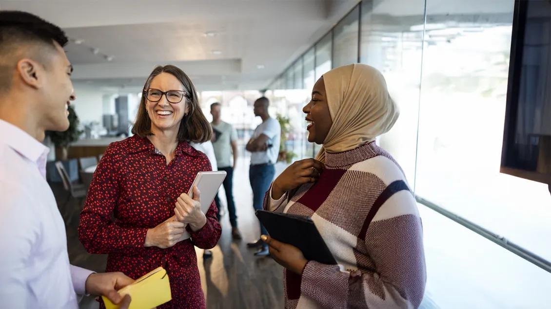 three professionals talking and smiling at an event