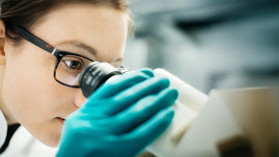 woman in lab looking into microscope