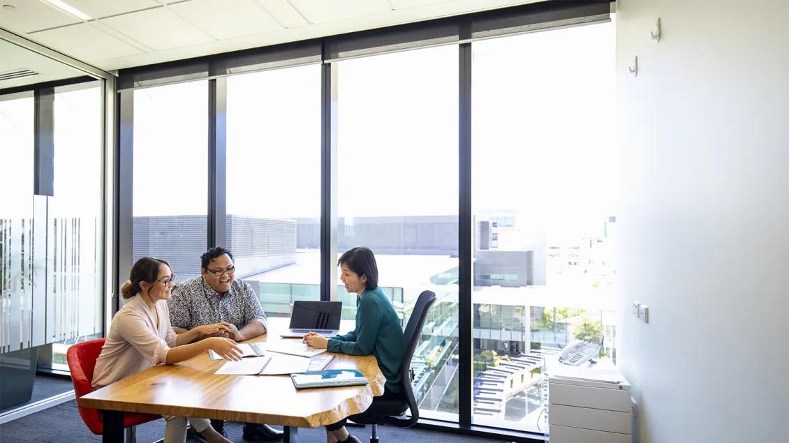 three people speaking in a conference room