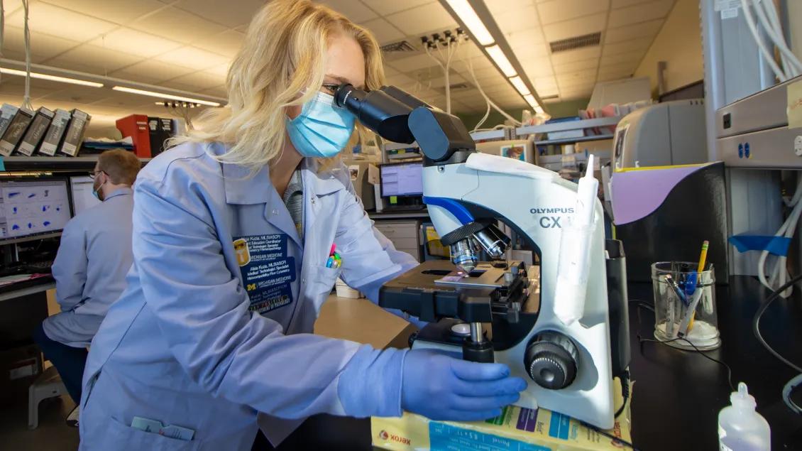 researcher working in a lab looking into a microscope