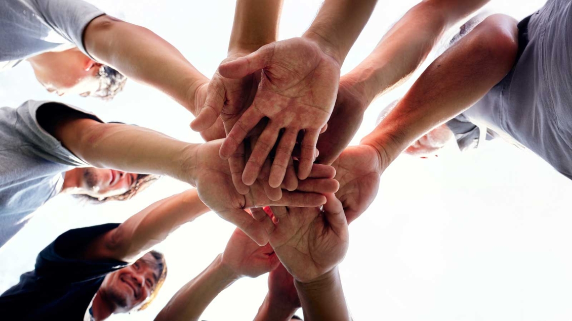 A group of people put their hands in the center to form a circle