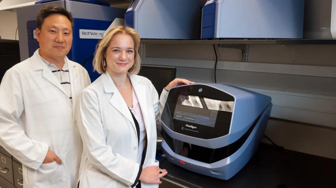 two researchers standing in lab with device
