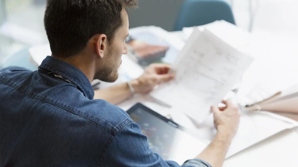 man reading stacks of paper at desk