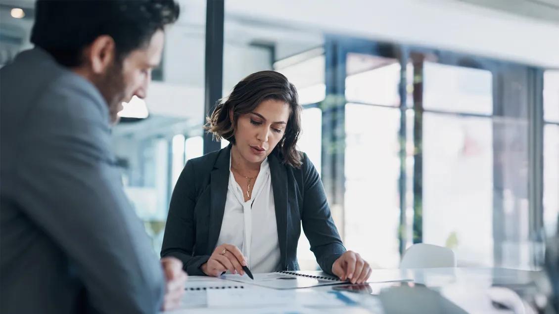 two people talking in a meeting and looking at paperwork