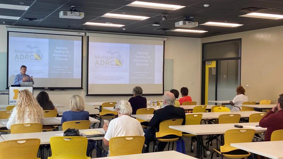 a faculty member presenting to a group of people at the Detroit Center 