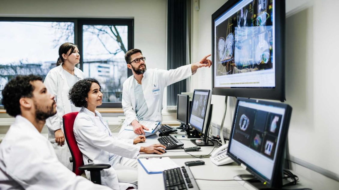 Group of four scientists discussion what they see on three computer screens