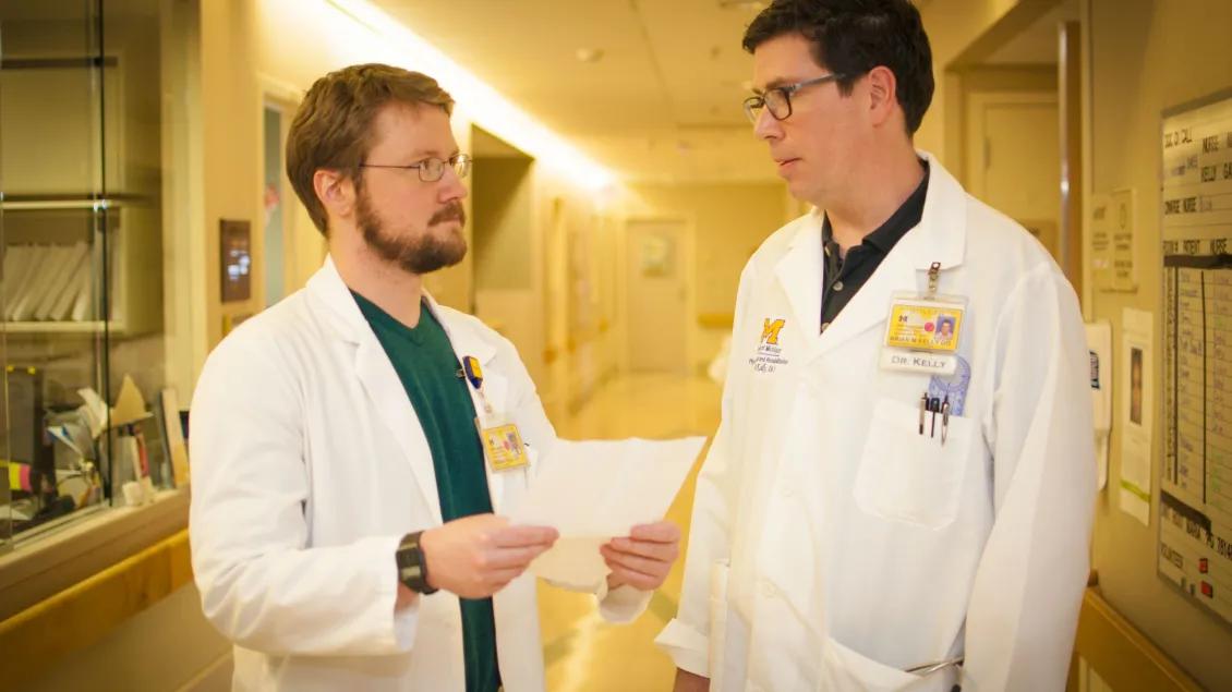 Two doctors stand discussing document