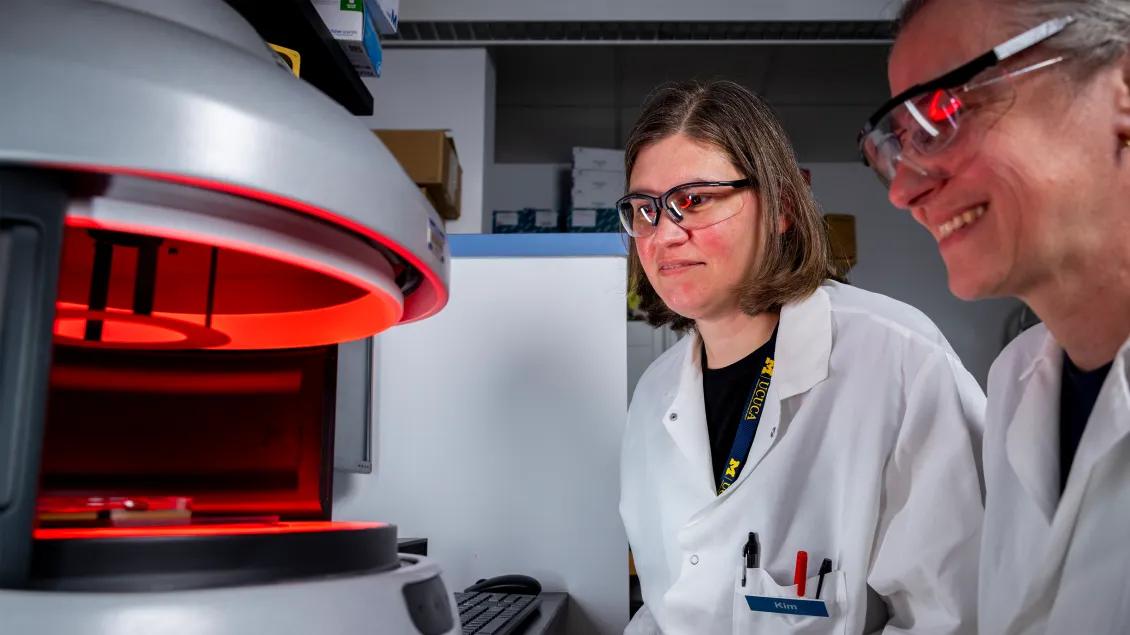 two researchers in lab looking at equipment
