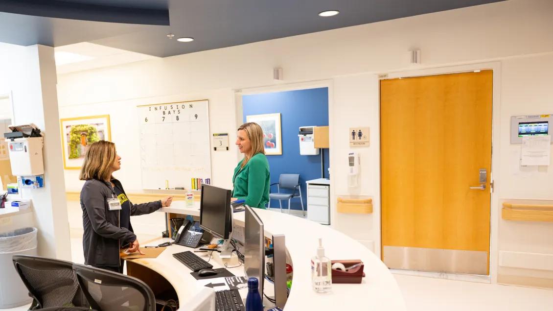 Photo of two women standing at the Michigan Clinical Research Unit welcome desk talking