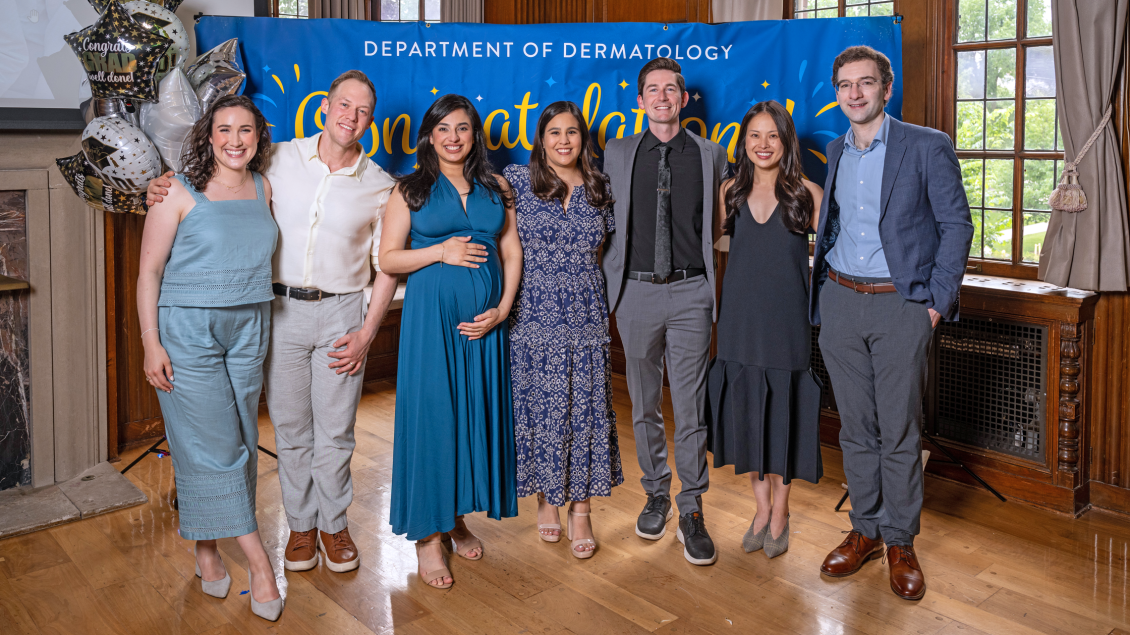 a group of 7 people standing in front of a banner that reads "Department of Dermatology - Congratulations!"