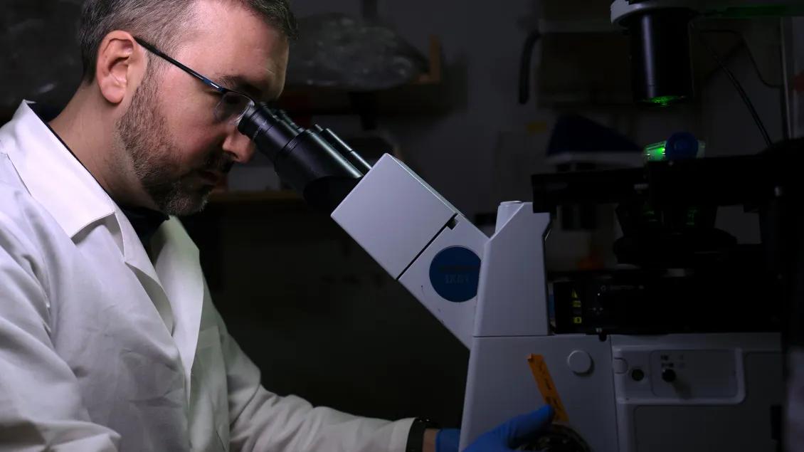 Man sitting in front of a microscope