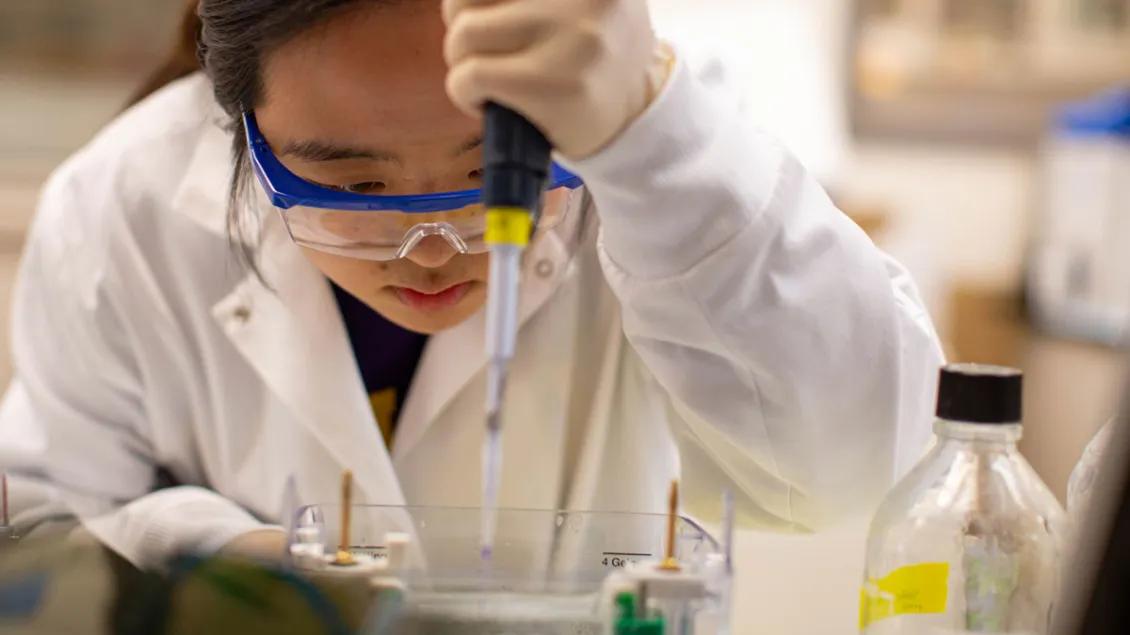 Young asian lab technician uses pipette