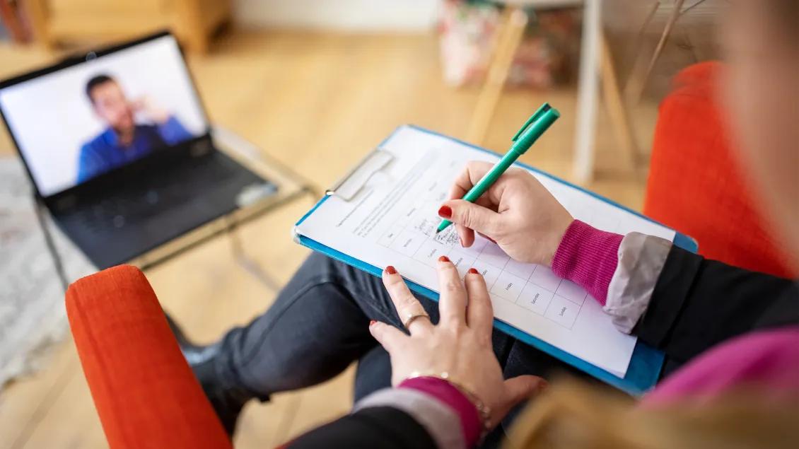 close-up of person taking notes in zoom meeting