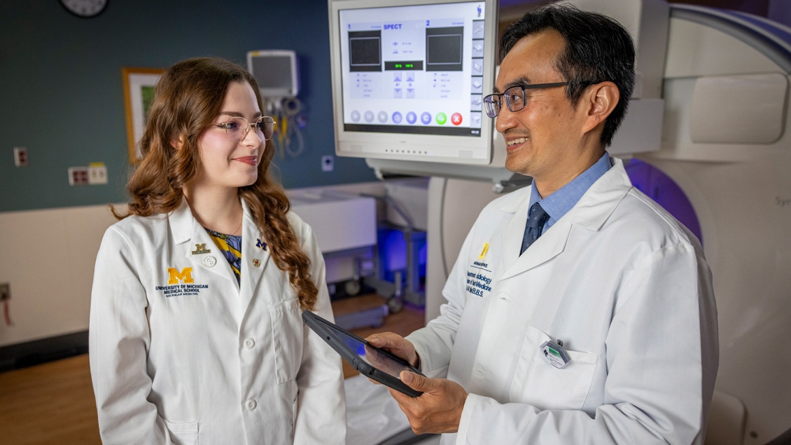 Doctor talks to med student while holding tablet