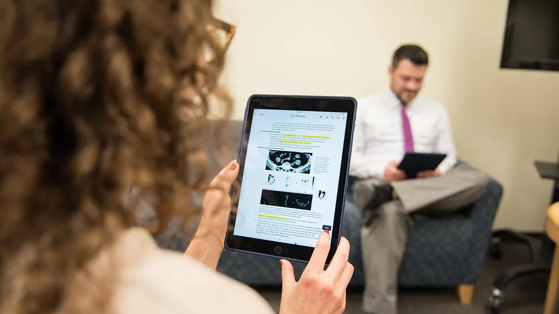 Rear view of a woman studying MRI data on a tablet screen