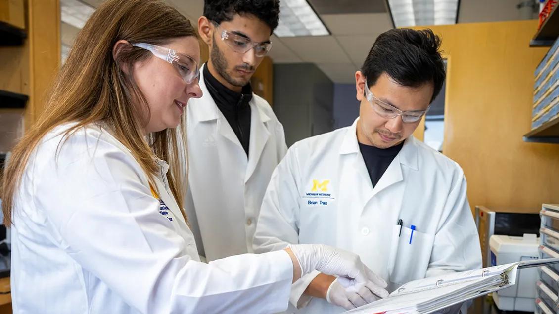 three genetic medicine doctors looking at binder