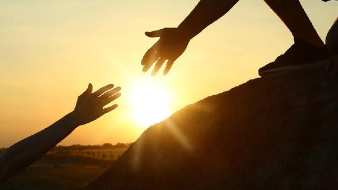 Two hands about to hold each other during a sunset
