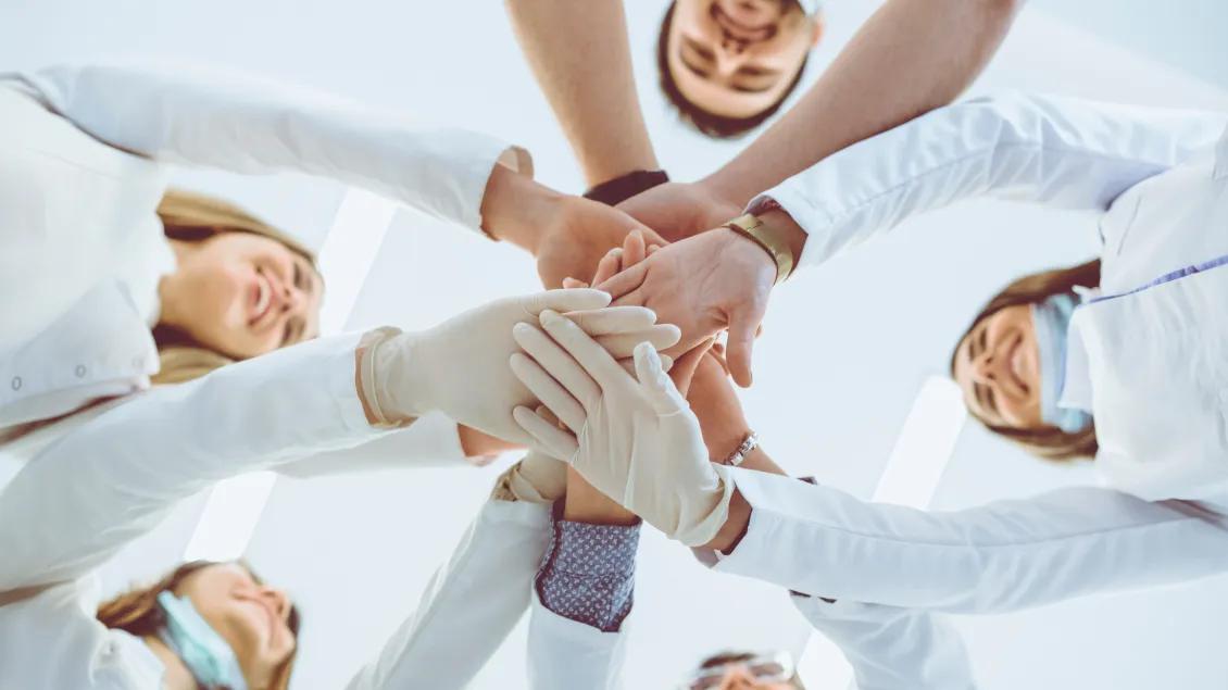 Multiethnic Medical Team Stacking Hands in Circle For Success