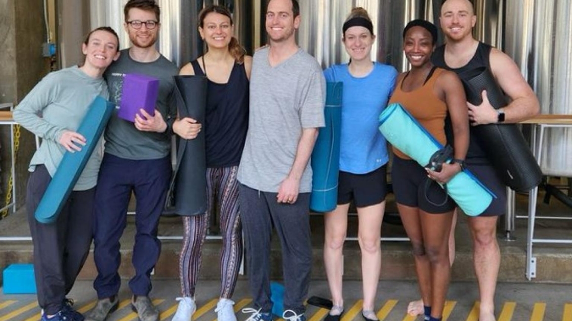 Psychiatry residents posing together holding rolled up yoga mats.