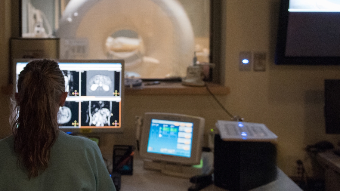 Radiology provider looks at a scan on the computer overlooking the MRI room
