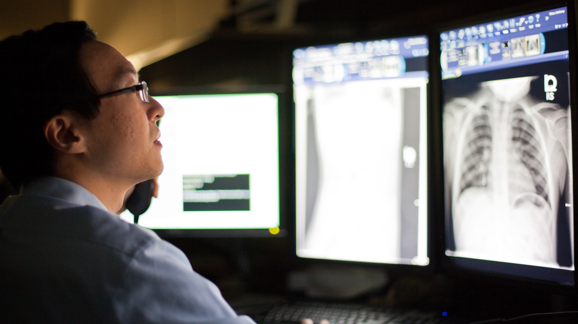 Male radiologist looks at x-rays on computer