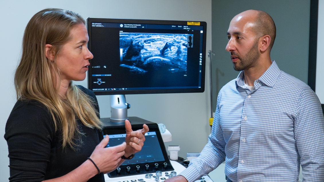 Woman speaks with man in front of medical imaging