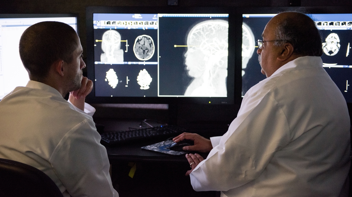 Two male Neuroradiologists look at scan image