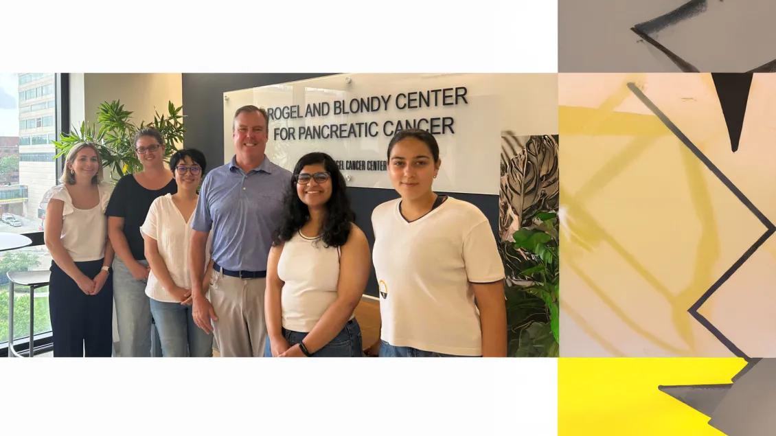 Rae Lab team members standing in front of a sign for the Rogel and Blondy Center Pancreatic Cancer