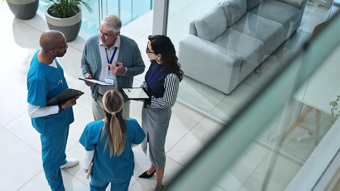 group of four medical professionals talking in a lobby