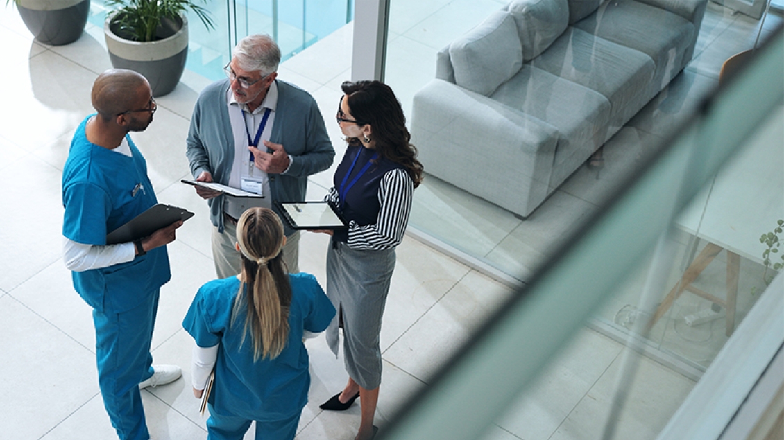 group of four medical professionals talking in a lobby