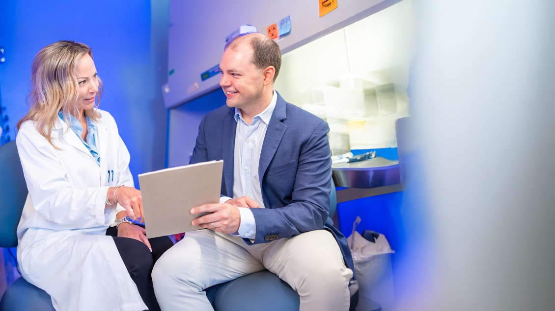 two researchers talking and smiling in a lab looking at a document