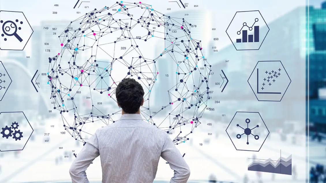 man stands in front of a screen filled with data points