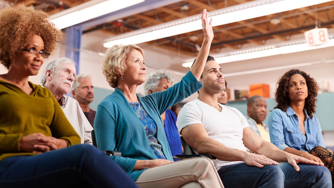 Men, women, young and old sit at a community meeting