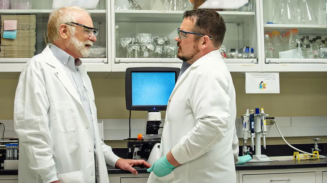 Dr. Max Wicha talks to his laboratory assistant in front of a computer