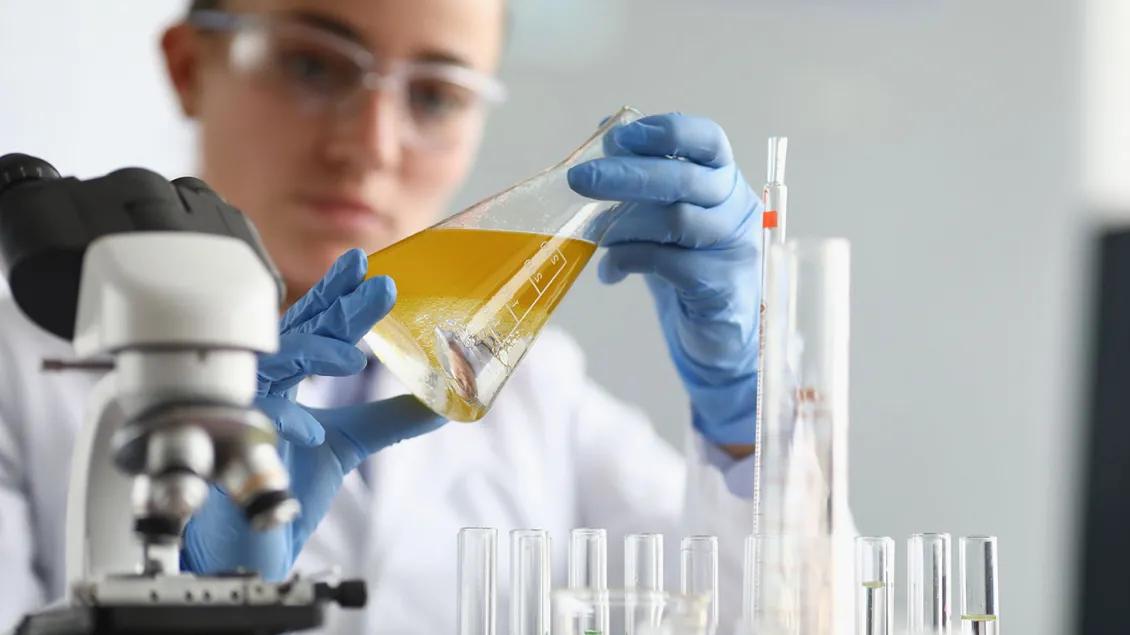 White woman examines liquid in a beaker
