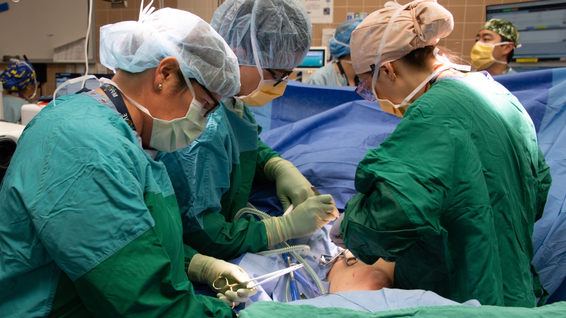 Surgeons wearing green scrubs operating on a patient