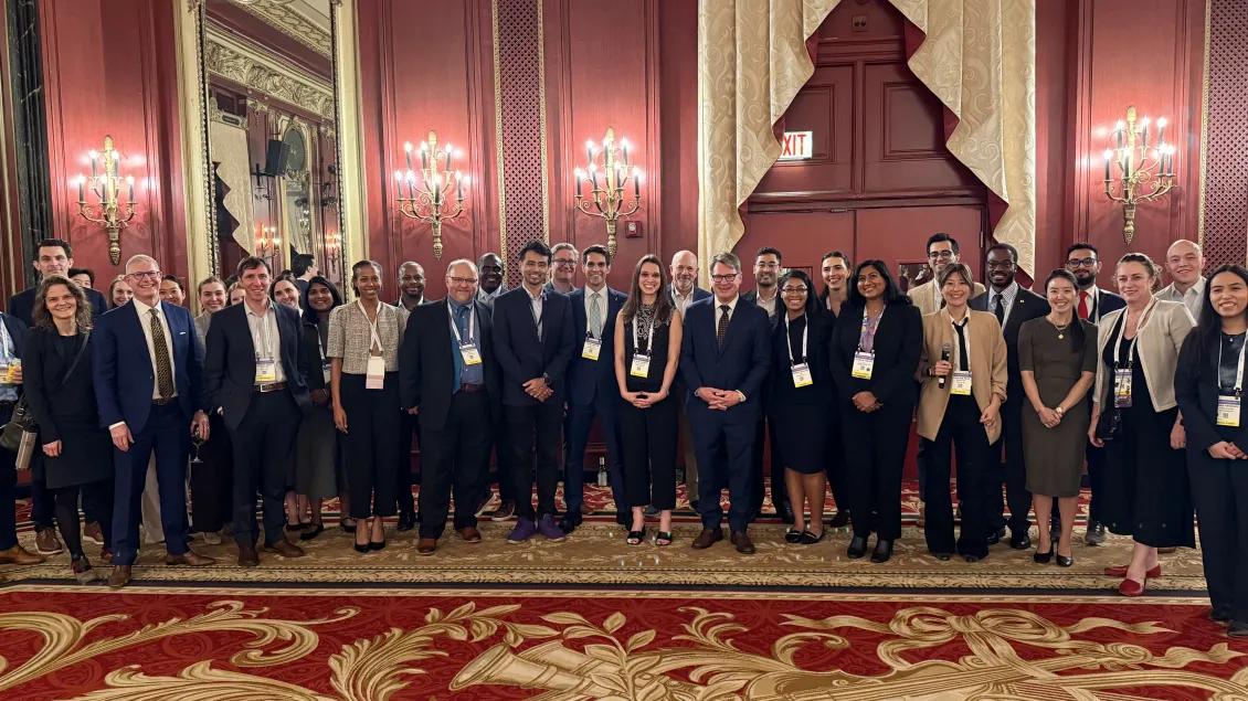 Group of smiling people in business attire in a red and gold ballroom