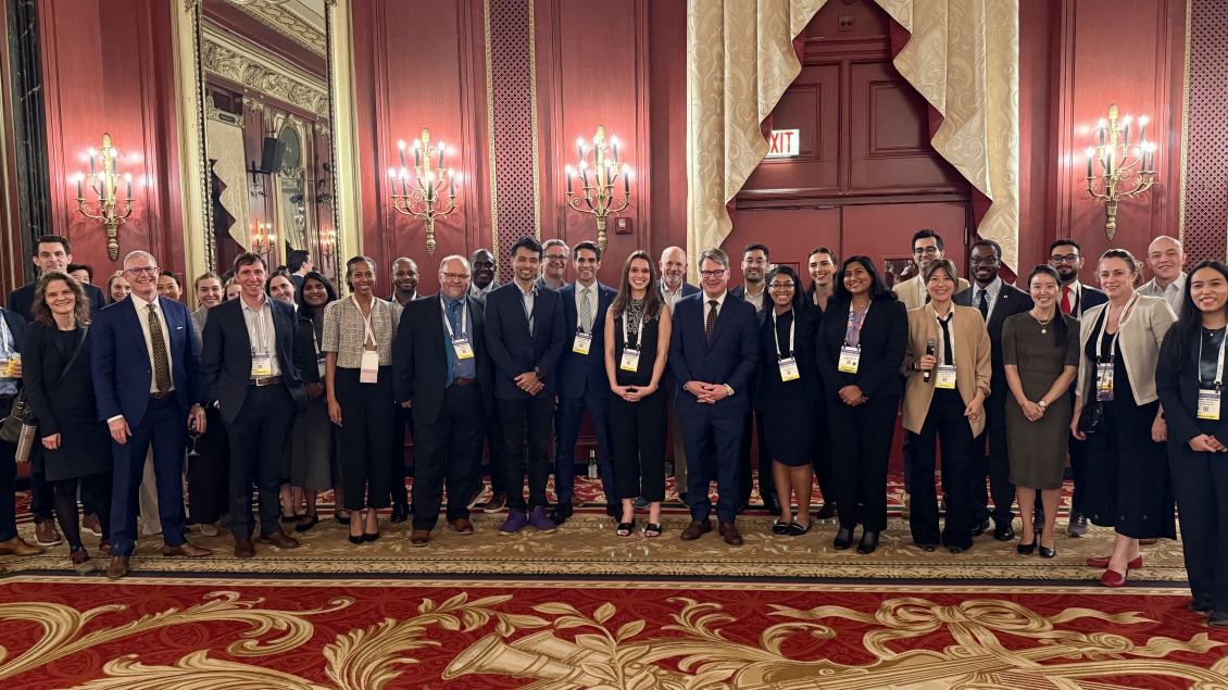 Group of smiling people in business attire in a red and gold ballroom