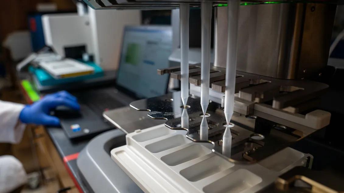 Laboratory equipment placing samples onto a tray controlled by a technician