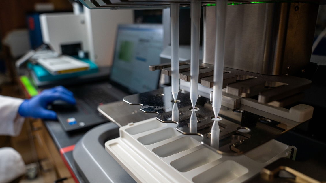 Laboratory equipment placing samples onto a tray controlled by a technician