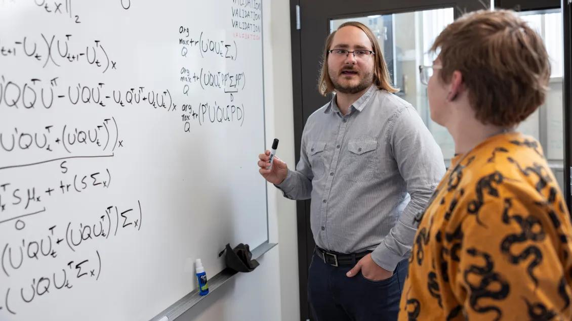 Researcher at whiteboard demonstrating his research