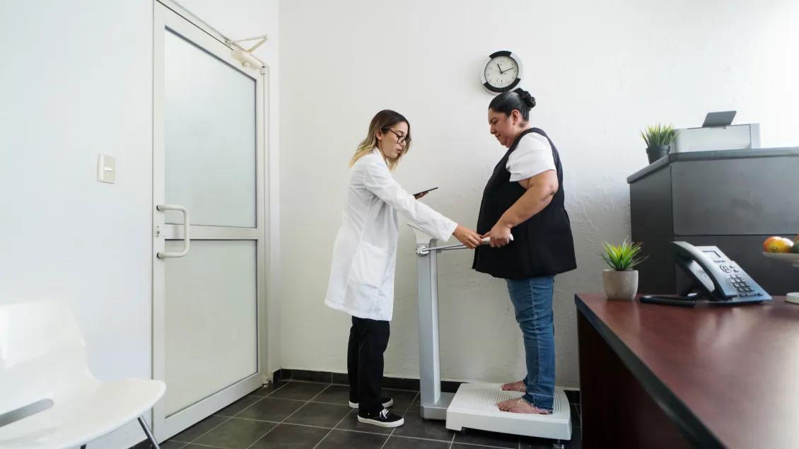 Healthcare provider assisting someone standing on a scale