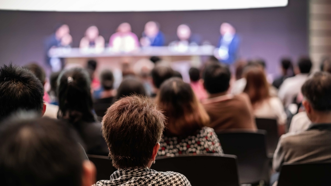Group of audience members listening to a panel in an auditorium
