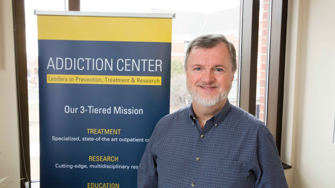 Person standing in front of an Addiction Center sign