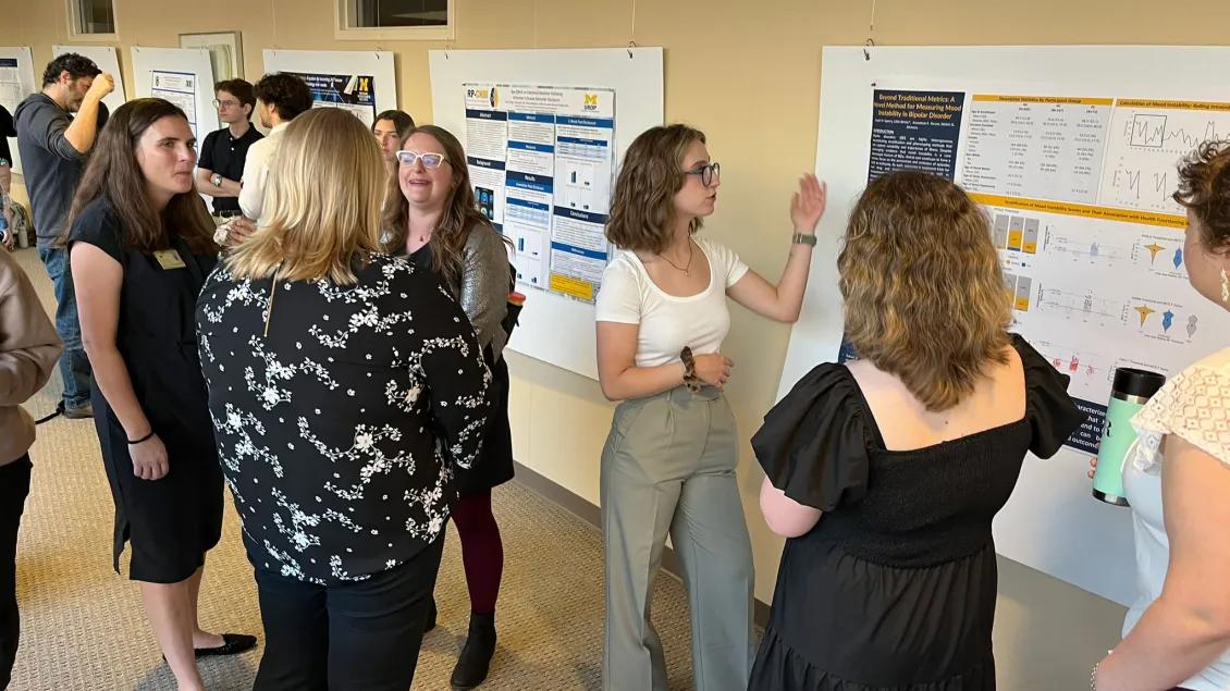 Team members standing in a hallway discussing research posters