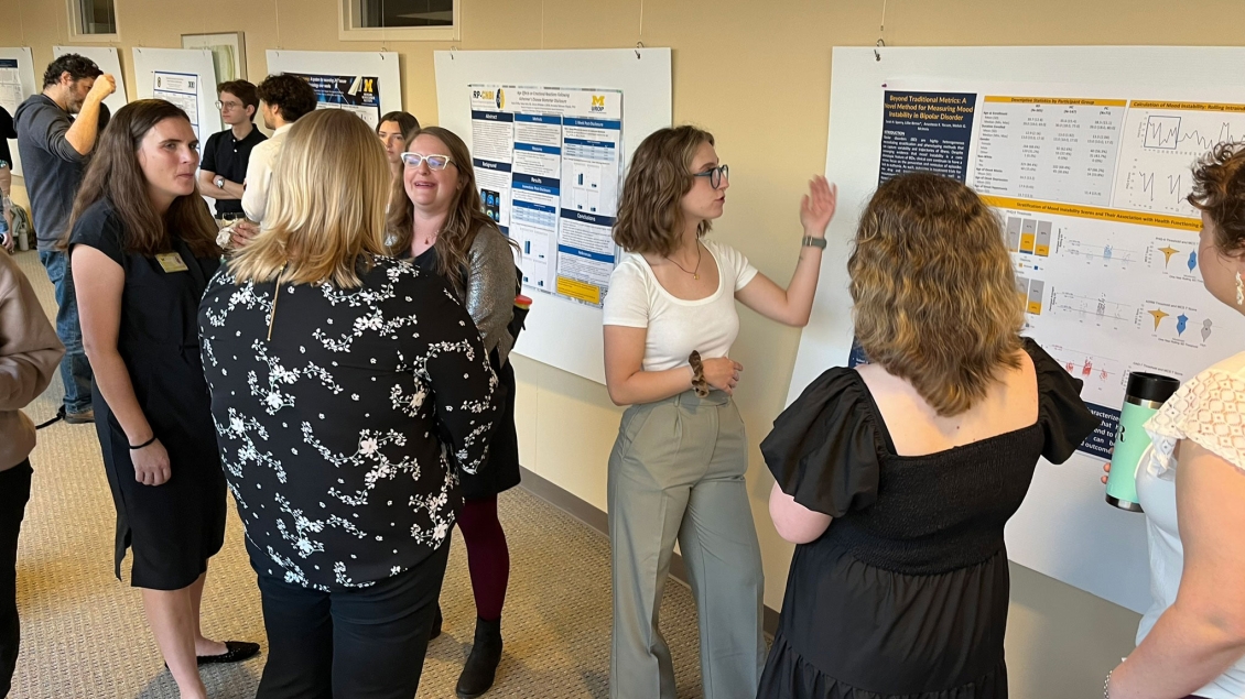 Team members standing in a hallway discussing research posters