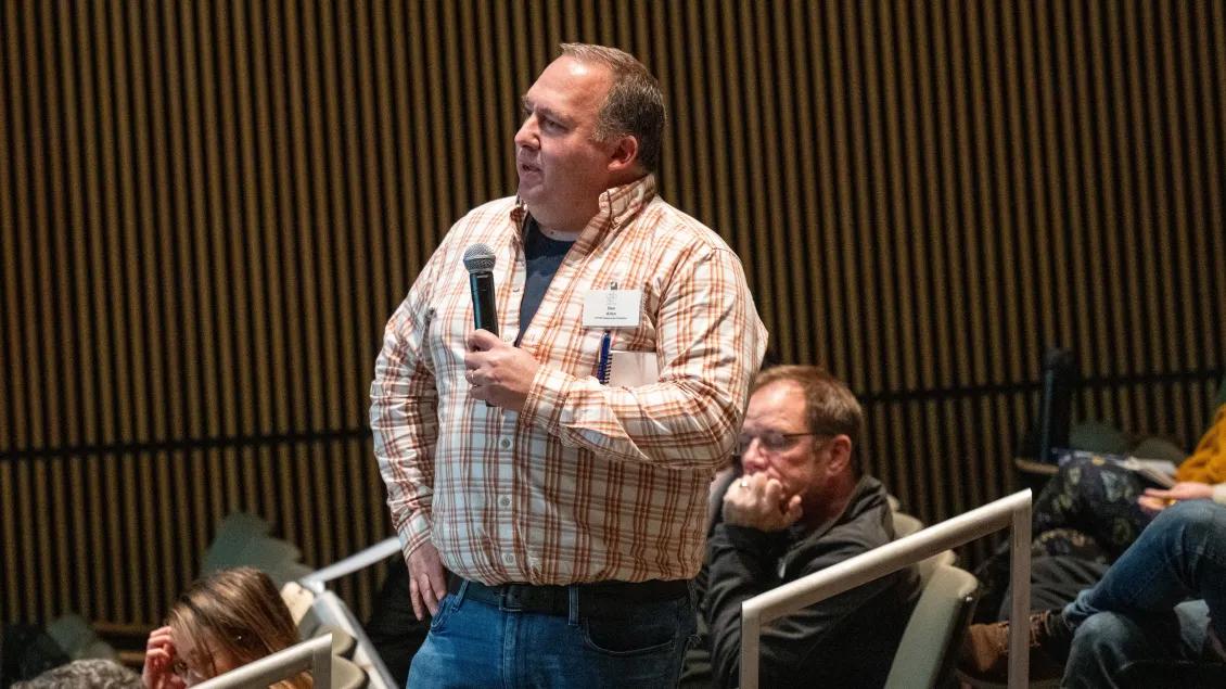 Benjamin Allen holding a microphone in a conference